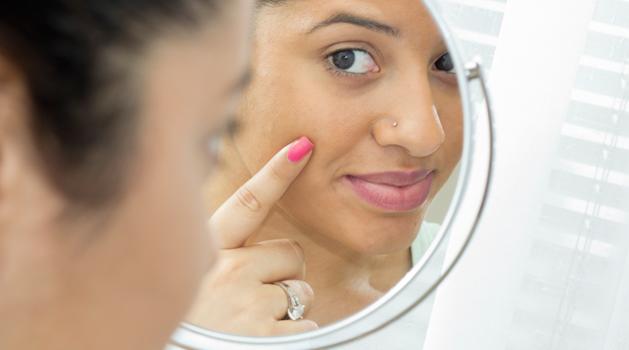 Femme regardant sa peau dans le miroir
